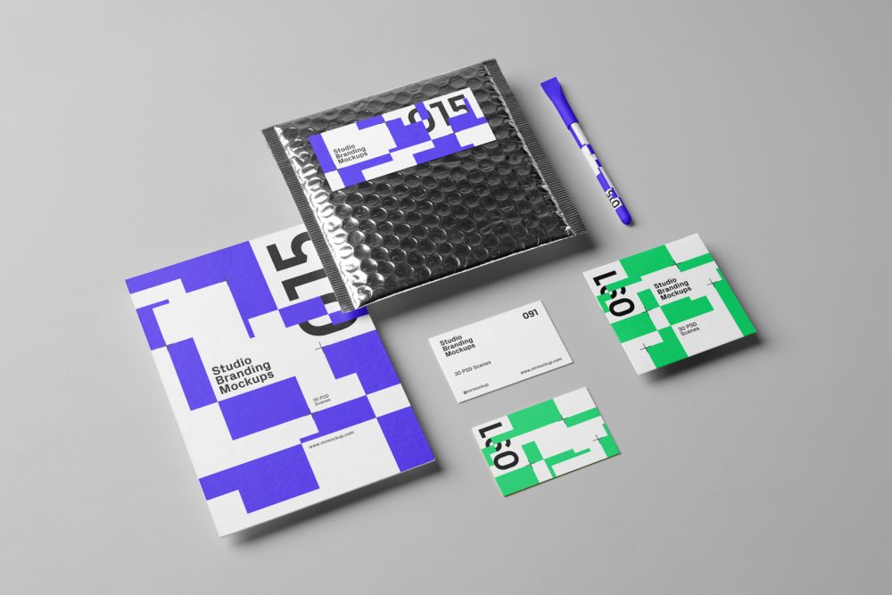 Seen from the above, a set of Branding Mockups elements like business cards, envelopes, pen and company paper with colorful design laying on the gray floor.