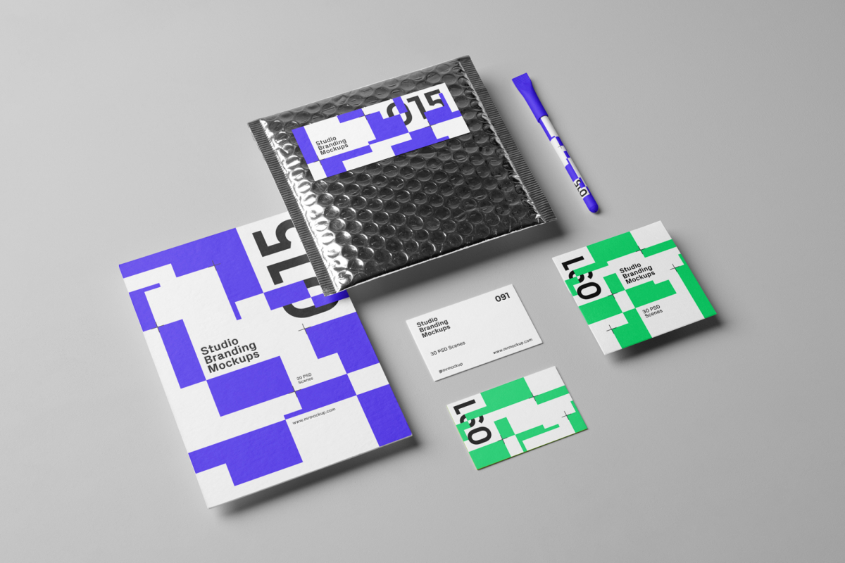 Seen from the above, a set of Branding Mockups elements like business cards, envelopes, pen and company paper with colorful design laying on the gray floor.