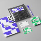 Seen from the above, a set of Branding Mockups elements like business cards, envelopes, pen and company paper with colorful design laying on the gray floor.