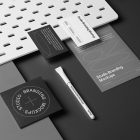 A set of Branding Mockups elements like business cards, envelope, pen, and company paper in composition with texture seen from the above laying on a gray box and black background.