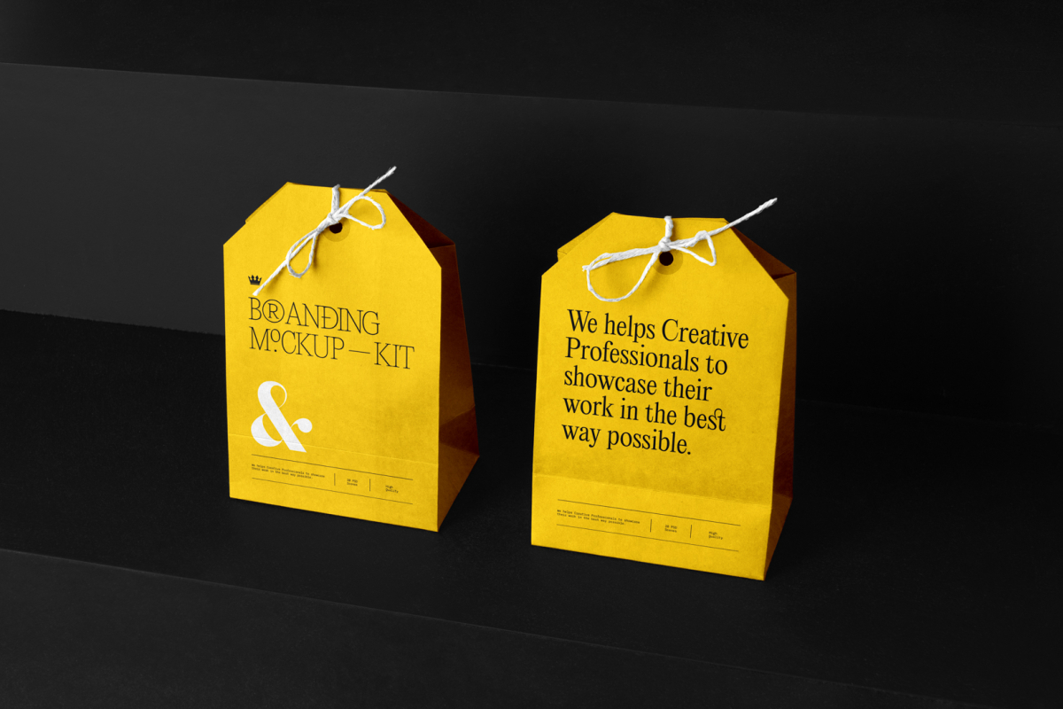 Two Decorative Paper Bags Branding Mockups Kit with a yellow design seen from above and standing on the black wooden stairs.