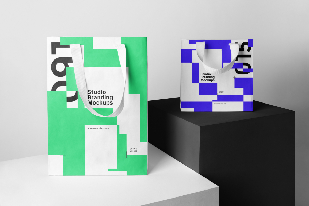 Seen from the front, Composition with Two Paper Shopping Bags, Branding Mockups standing on the white and black cubic against a gray background.