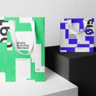 Seen from the front, Composition with Two Paper Shopping Bags, Branding Mockups standing on the white and black cubic against a gray background.