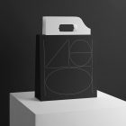 Black Paper Bag with Handle Branding Mockup with a minimalistic design standing on the white cubic on black background.