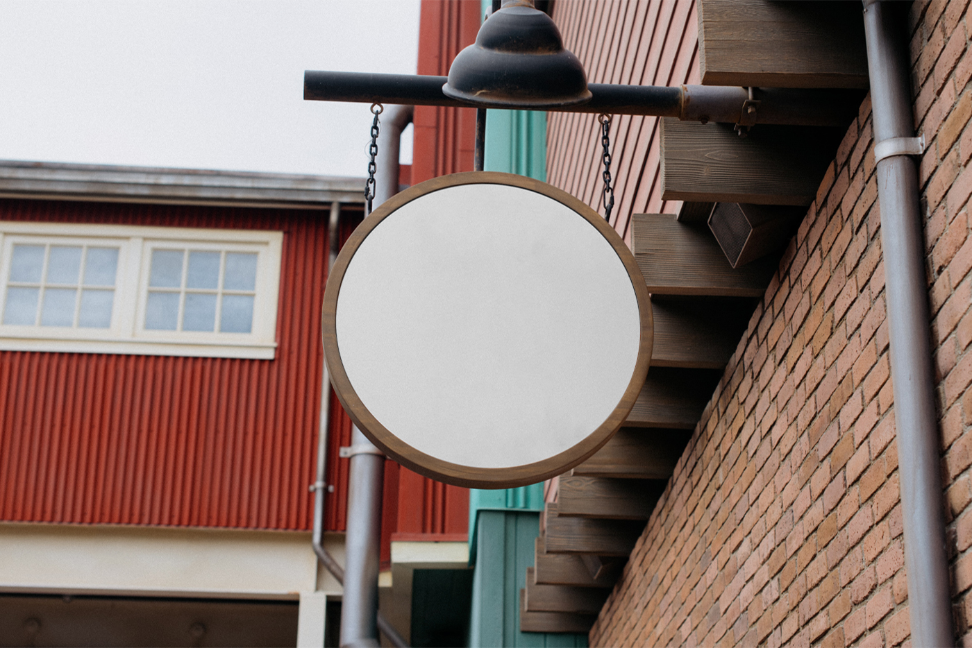 Front view, Blank Free Circle Sign Mockup with wooden frame hanging on the chains attached to metal tube and brick wall.