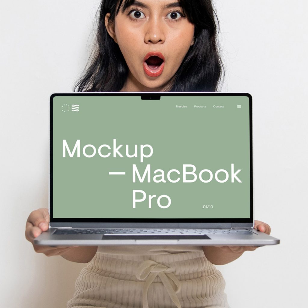 Free front view, Free MacBook Pro Mockup held in the hands of a woman with green hero page design against white wall in the background.