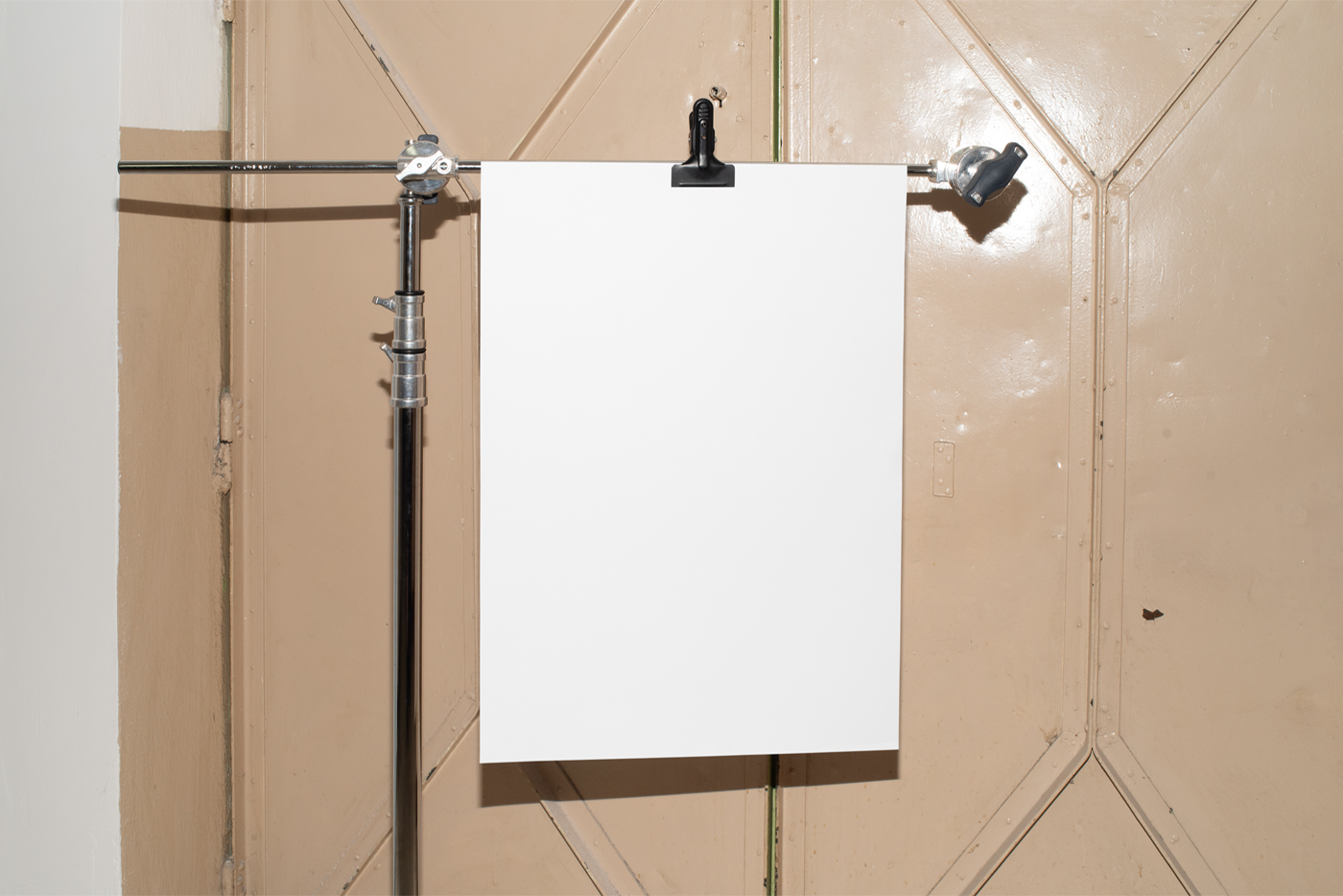 Free Blank Poster Hanging on Tripod Mockup against vintage magazine door in beige color.