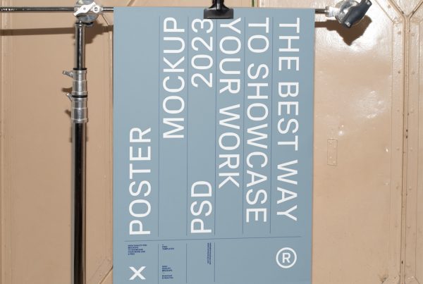 Free Poster Hanging on Tripod Mockup with bright blue design colors against vintage magazine door in beige color.