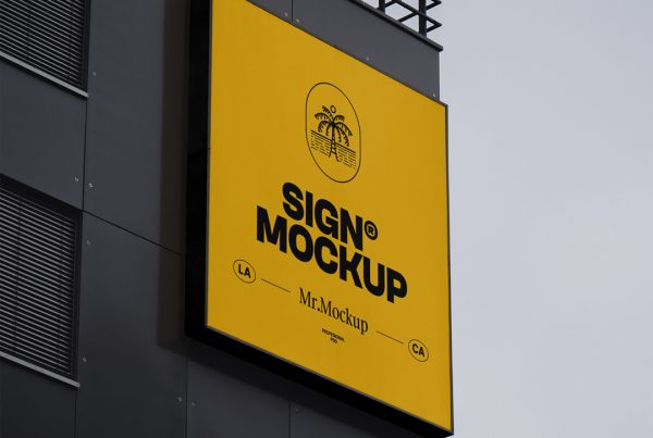 Bottom view, Free Sign on Building Mockup with orange and black design and typography is attached to the black building facade on the top.