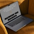 Seen from above, space gray MacBook Pro Mockup with gray design laying on the reddish yellow couch.