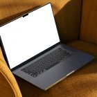 Seen from above, space gray blank MacBook Pro Mockup laying on the reddish yellow couch.