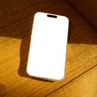 Seen from above, gold blank iPhone 14 Pro Mockup laying on the reddish yellow couch.