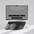 Front view, MacBook Pro Mockup with gray design standing on the big rock against a bright gray background.