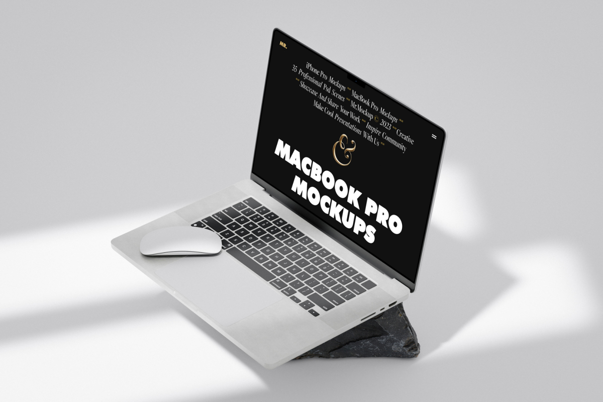 Front view, silver MacBook Pro Mockup with black design standing on the gray/black rock laying on the bright gray floor.