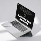 Front view, silver MacBook Pro Mockup with black design standing on the gray/black rock laying on the bright gray floor.