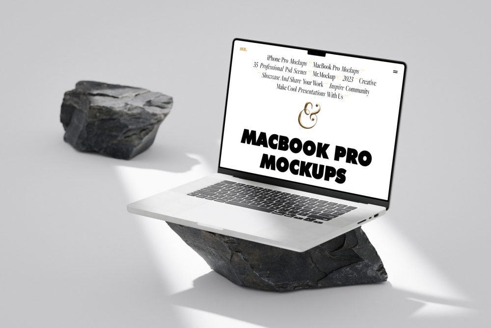 Front view, MacBook Pro Mockup with white design standing on the big piece of rock laying on the bright gray floor against second gray/black rock and gray wall in the background.