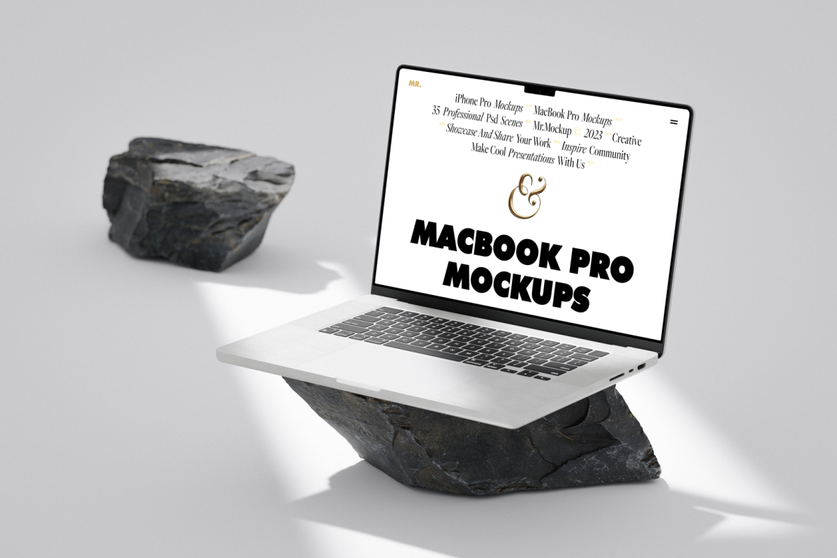 Front view, MacBook Pro Mockup with white design standing on the big piece of rock laying on the bright gray floor against second gray/black rock and gray wall in the background.