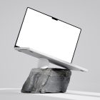 Front view, blank MacBook Pro Mockup standing on the white apple mouse and piece of rock against bright gray floor and wall.