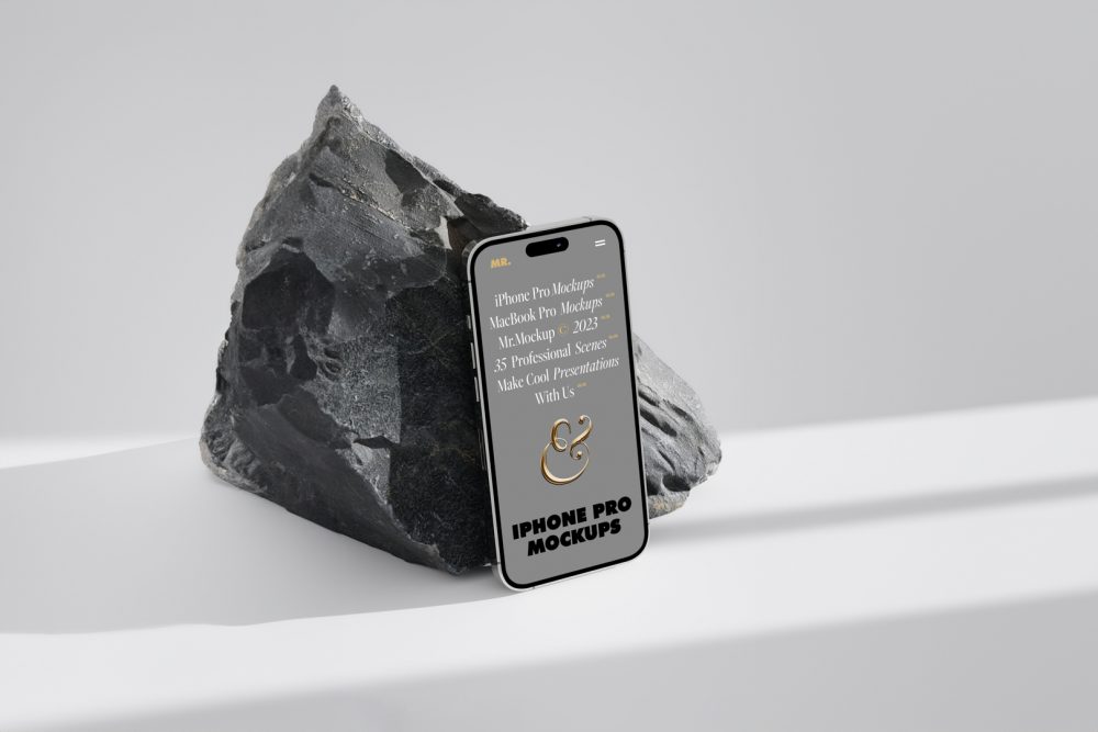 Seen from above, the iPhone 14 Pro Mockup with gray design based on the big piece of rock standing on the bright gray floor.