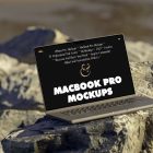 Front view, space gray MacBook Pro Mockup with black design standing on the sunny rocks on the beach against water in the background.