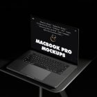 Seen from above, MacBook Pro Mockup with black design standing on the black desk against a deep black background.