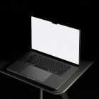 Seen from above, blank MacBook Pro Mockup standing on the black desk against a deep black background.