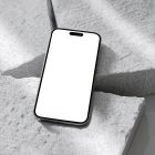 Seen from above, blank iPhone 14 Pro Mockup laying on the pieces of a styrofoam laying on the white floor.