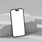 Front view, blank iPhone 14 Pro Mockup based on the piece of a styrofoam and standing on the white floor against white wall.