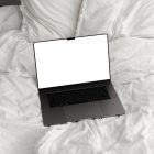 Front view, blank MacBook Pro Device Mockups laying on the white linen on bed.