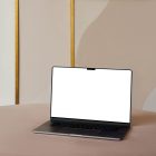 Front view, blank MacBook Pro Device Mockups laying on the beige table against the wall with white, gold and beige decoration in the background.