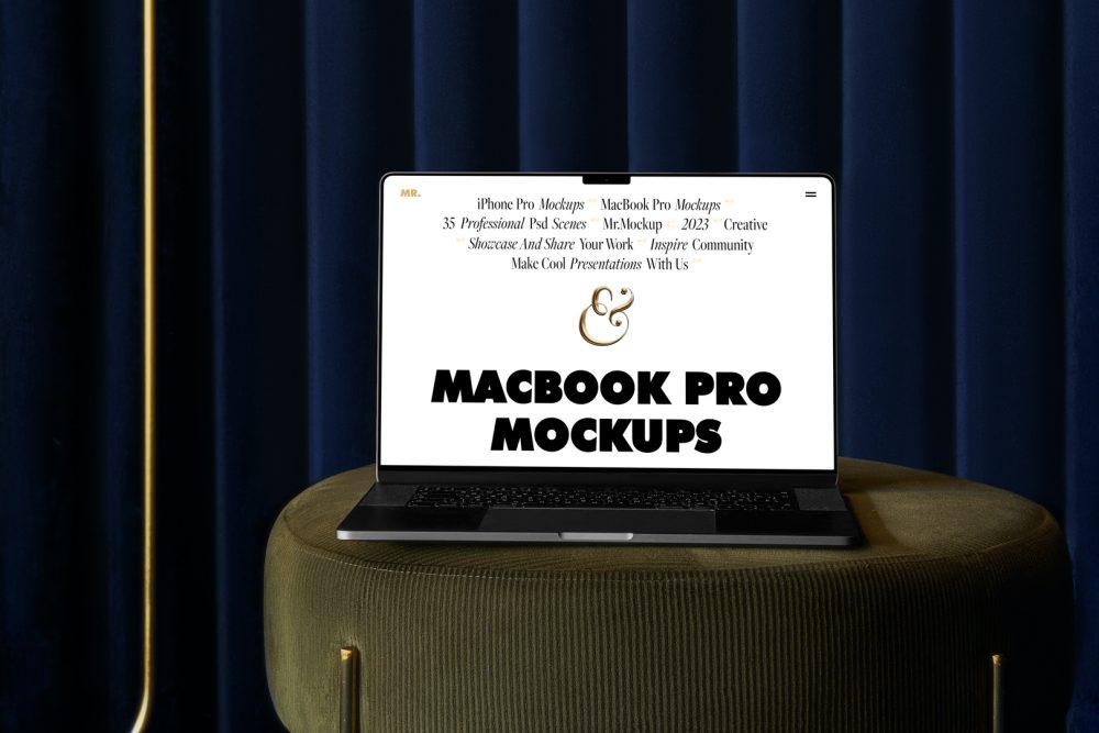 Front view MacBook Pro Mockups with white design laying on the bottle green pouf with gold elements against a deep blue curtain in the background.