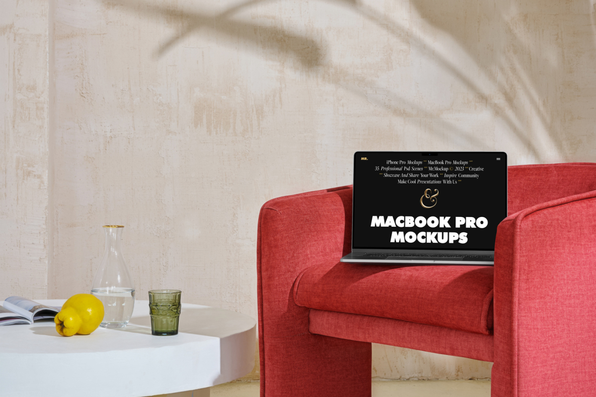Front view MacBook Pro Mockups with black design laying on the red armchair against a wall in the background.