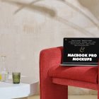 Front view MacBook Pro Mockups with black design laying on the red armchair against a wall in the background.