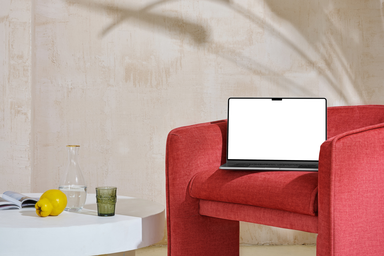Front view, blank MacBook Pro Device Mockups laying on the red armchair against a wall in the background.