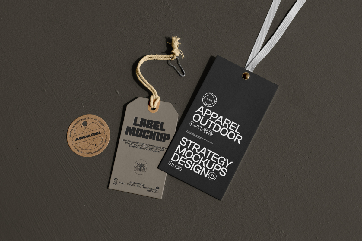 Seen from above, three labels mockups. Black Rectangle label mockup with white typographic design with a white string attached. Craft figure label mockup with black typographic design with a craft color string attached. Craft circle label mockup with a black design on it. All labels are on dark concrete.