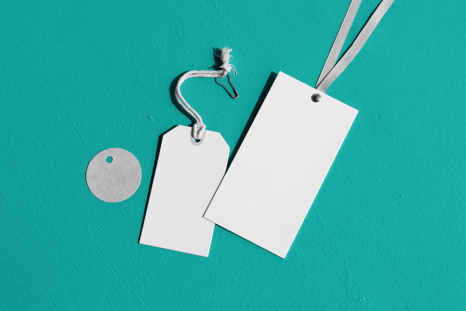 Seen from above, three white labels mockups laying on the celadon concrete.