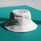 Front view, White Bucket Hat Mockup laying on the celadon concrete against white wall.