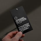 Front view, black label mockup with white typographic design in men's left hand against a dark beige wall.