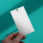 Front view, white label mockup in men's left hand against a celadon wall.