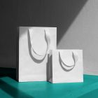 Front view, White Paper Bag Mockups standing on the celadon concrete against on the white wall.