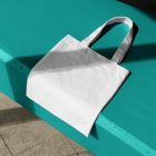 Seen from above, White Canvas Bag Mockup laying on the celadon concrete against the marble floor.