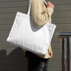 Front view, Men wearing a White Canvas Bag Mockup against rotten green color wall.