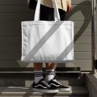 Front view, Men in vans shoes wearing White Big Canvas Bag Mockup against a rotten green wall.