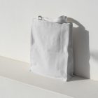 Seen from above, White Big Canvas Bag Mockup with standing on the white concrete against a white textured wall.