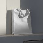 Front view, White Canvas Bag Mockup standing on the white windowsill against on the white wall in shadow.