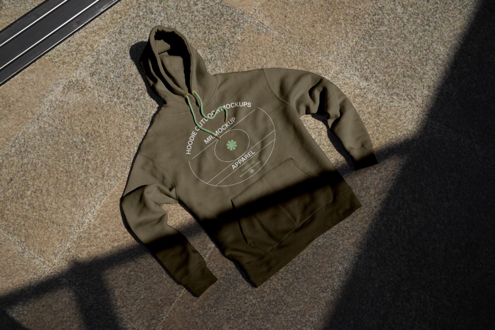 Seen from above, rotten green Hoodie Mockup with bright green strips laying on the ginger marble floor.