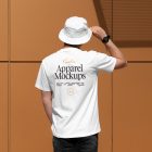 Front view, man with his back turned, wearing a white T-shirt Mockup and white Bucket Hat Mockup standing against on the gold wall.