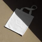 Seen from above, White Canvas Bag Mockup laying on the gold floor.