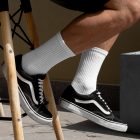 Front view, Men wearing vans shoes and white Socks Mockup sitting on a chair against a gold wall.