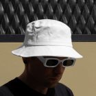 Front view, Men wearing a White Bucket Hat Mockup against a black fence.